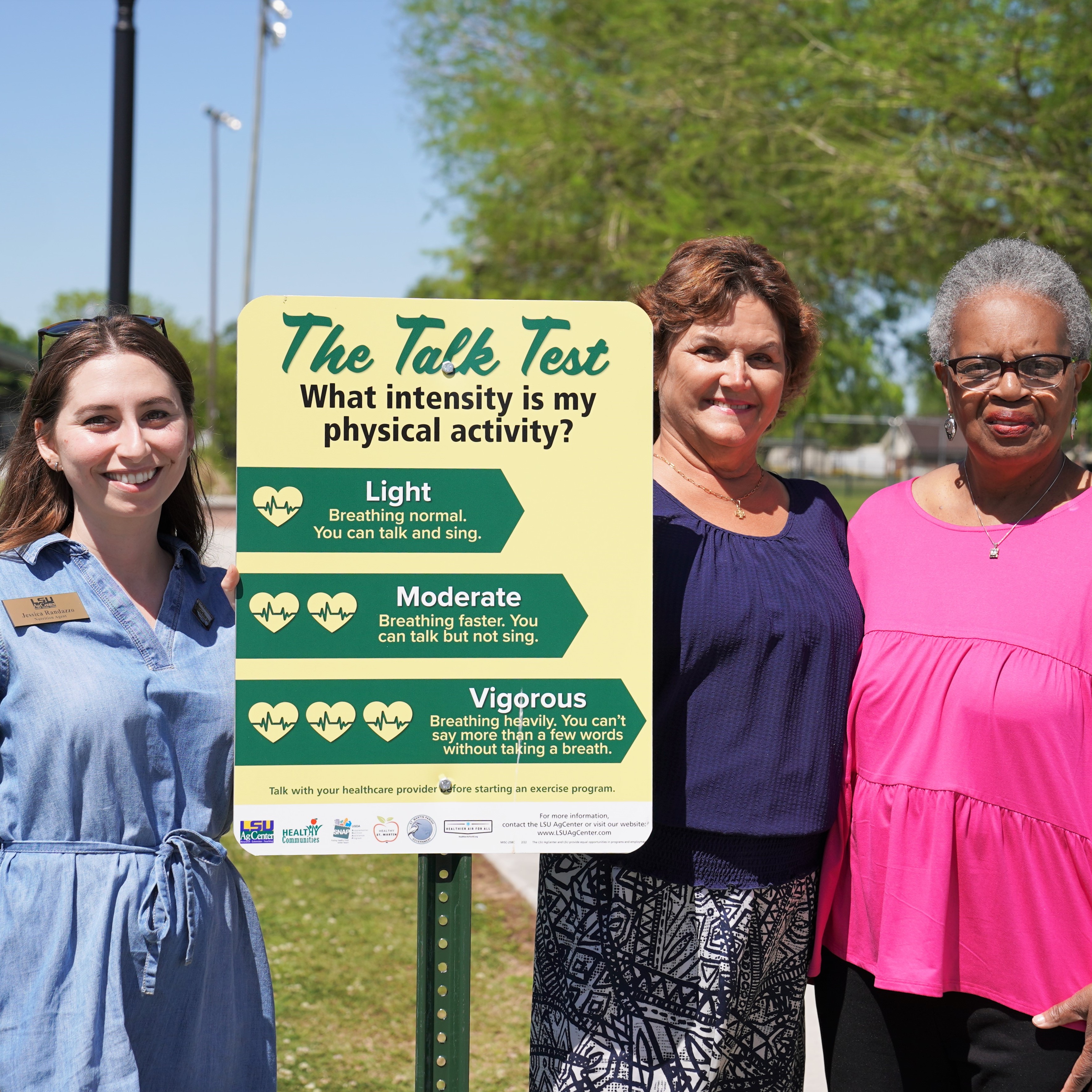 Three women standing next to a park sign